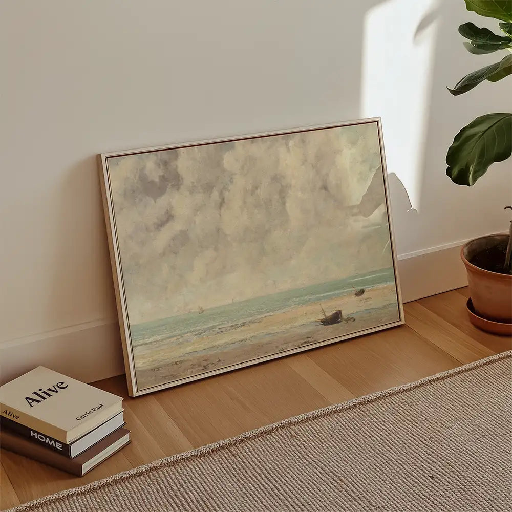 Painting of a seascape featuring boats on the water and cloudy skies, displayed against a neutral wall with a potted plant and stacked books nearby.