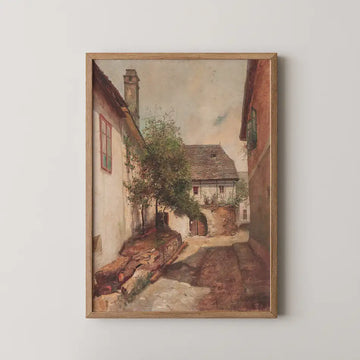 A serene painting of a rustic village street scene with charming houses, greenery, and a cloudy sky, framed in wood.