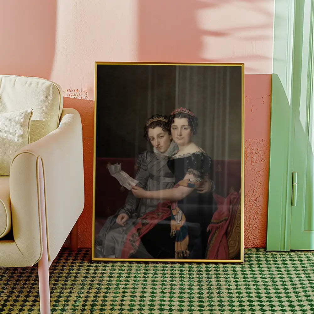 Portrait of two women in elegant dresses, framed and leaning against a wall next to a beige sofa in a stylish room setting.