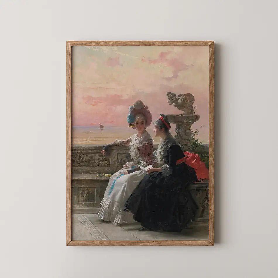 Painting of two women in elegant dresses sitting by a seaside terrace at sunset, framed in wood.