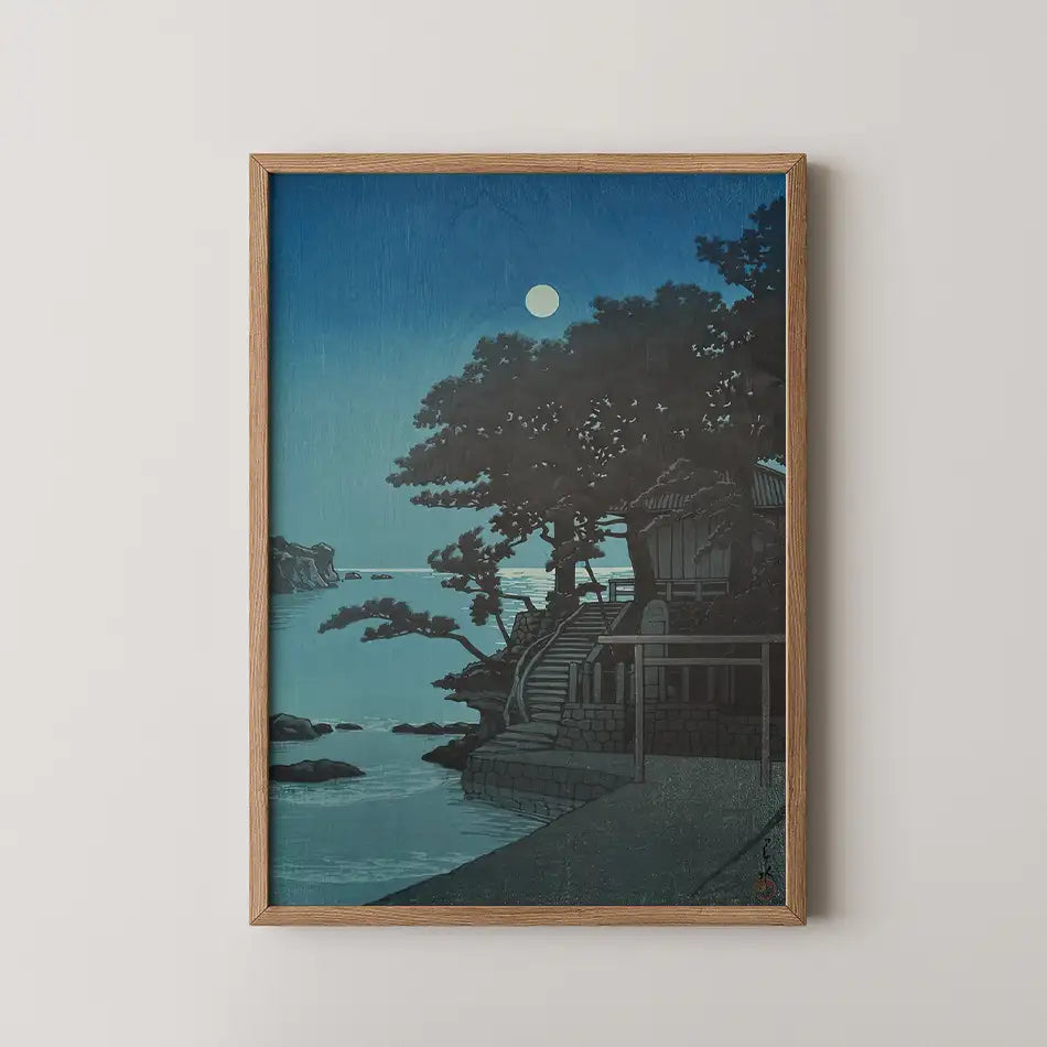 Framed painting of a serene coastal scene at night with a full moon above, featuring a house among trees and rocky shores.