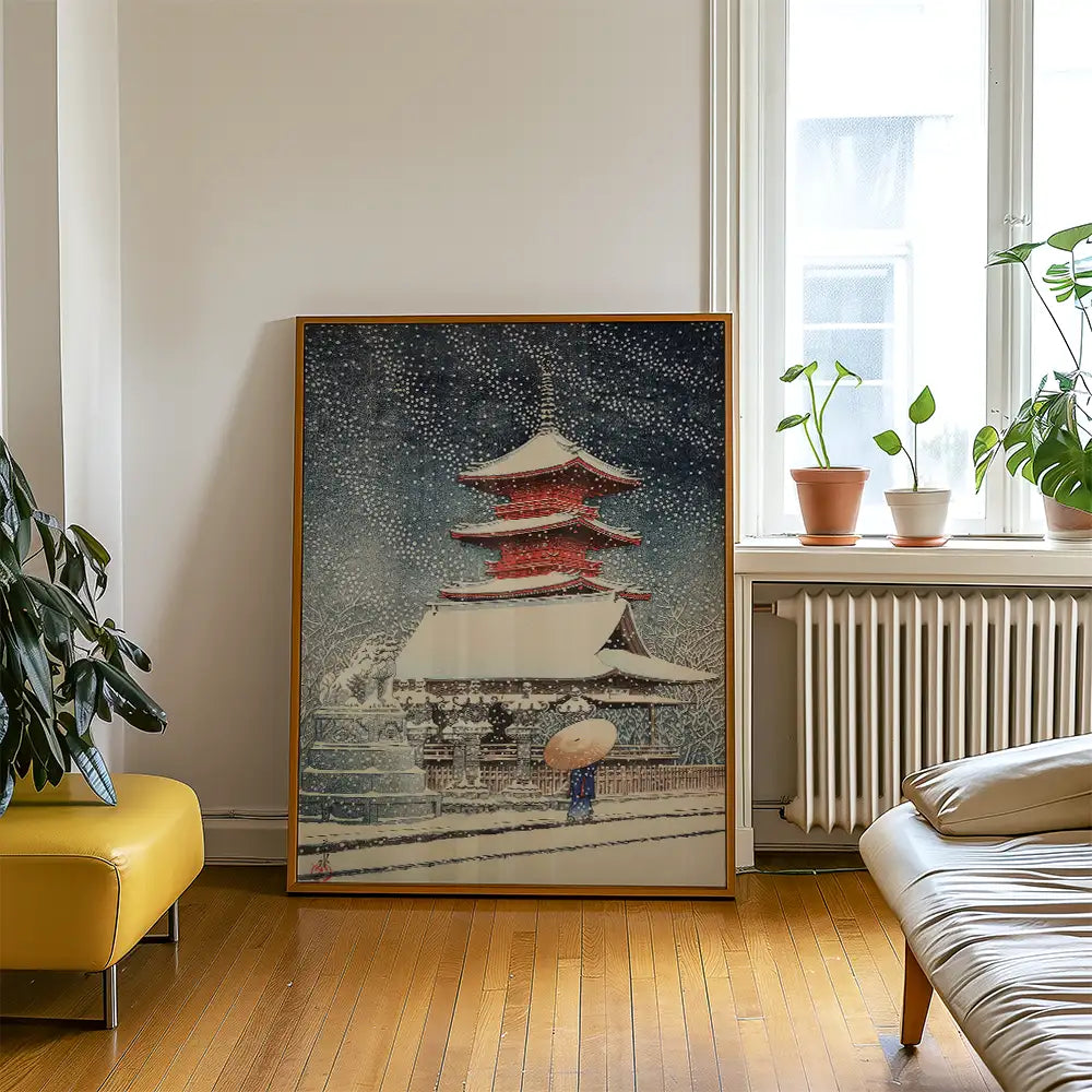 Painting of a traditional Japanese pagoda in the snow, displayed in a modern living room with potted plants and a yellow sofa.