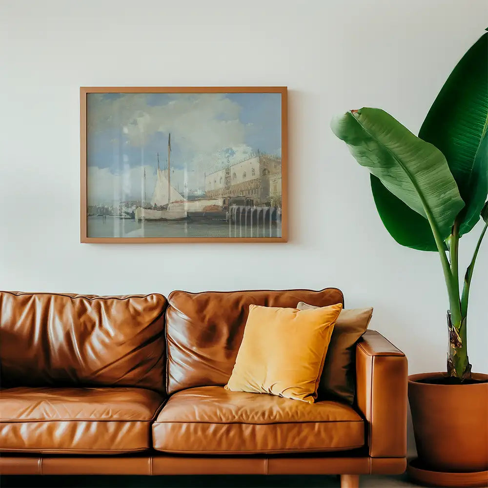 Framed painting of a coastal scene with sailboats, displayed above a brown leather sofa and a potted plant.