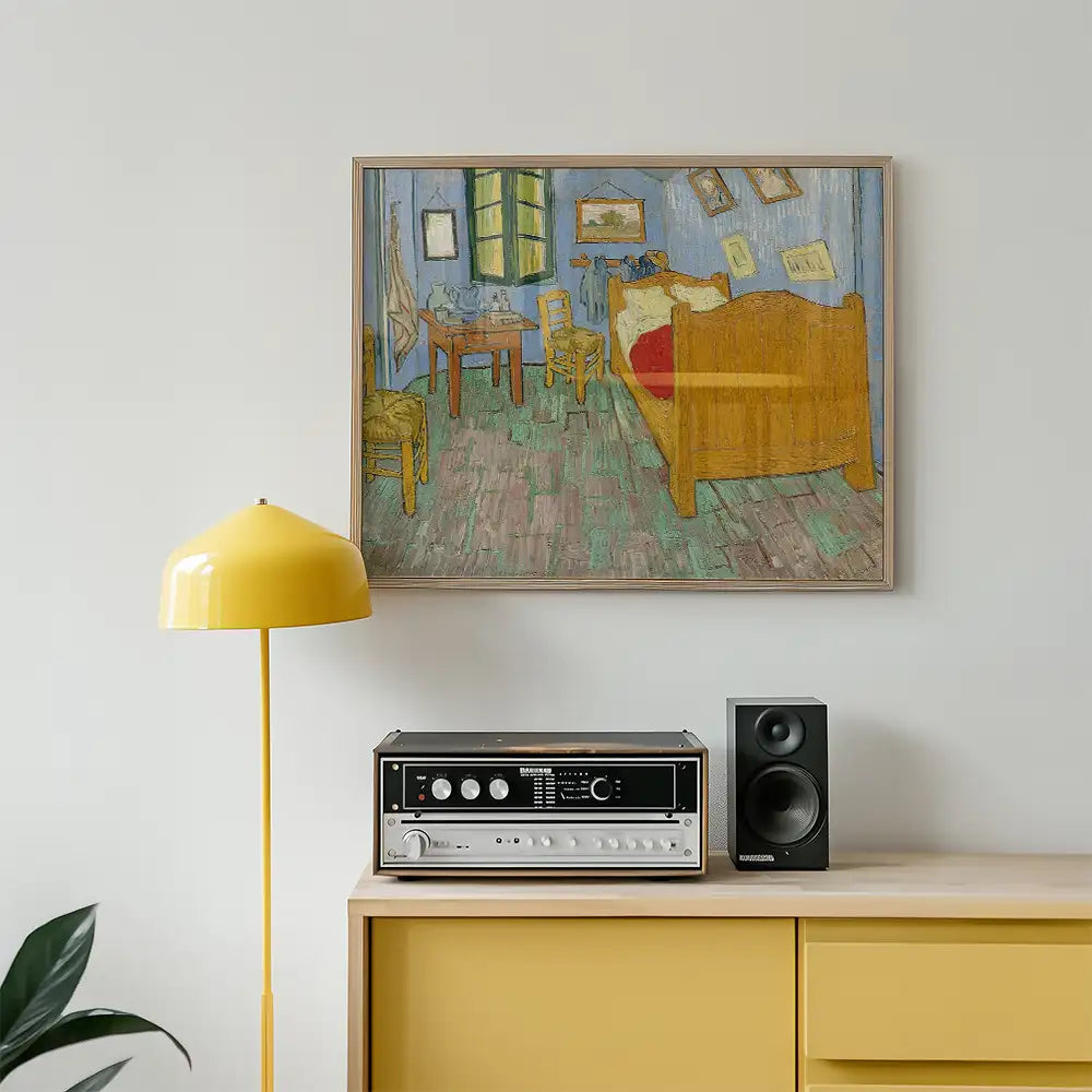 Painting of a cozy bedroom interior featuring a bed, chairs, and a table, framed and mounted on a wall above a yellow lamp and vintage audio equipment.