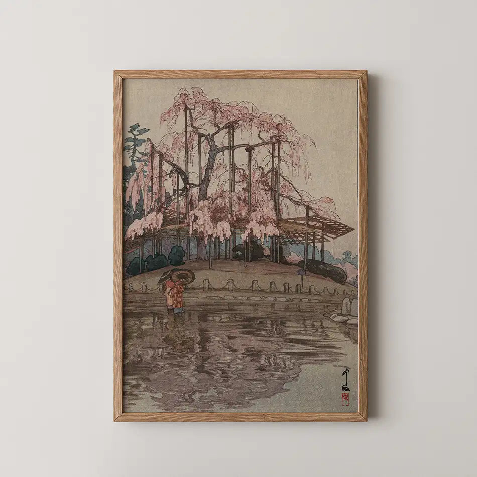 Framed painting of a serene landscape featuring a pink cherry blossom tree, a pond, and two figures holding an umbrella, evoking a tranquil atmosphere.