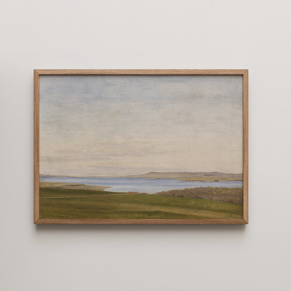 Painting of a serene landscape featuring a body of water, green fields, and distant hills, framed in natural wood.