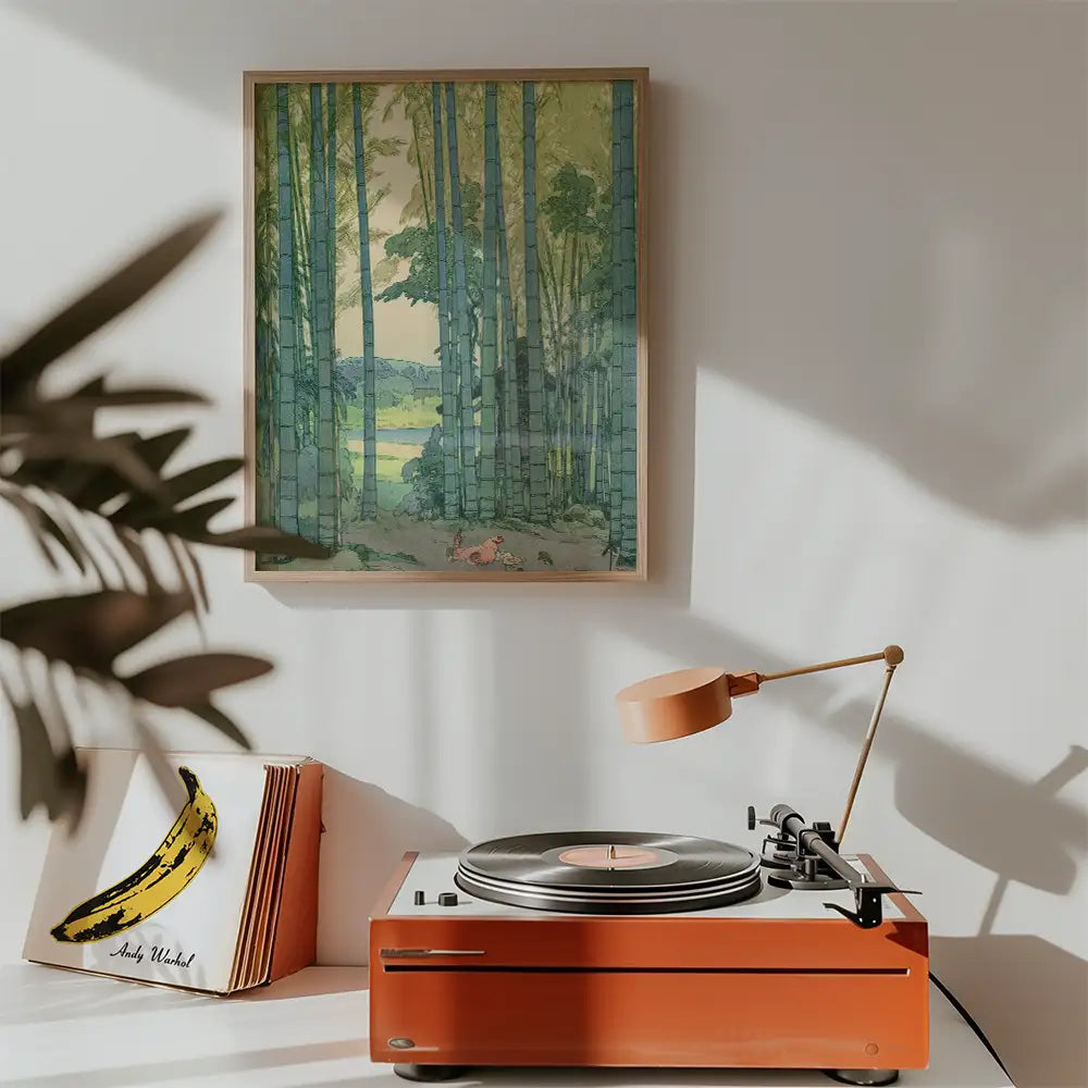 A framed painting of bamboo trees hanging on a wall above a vintage record player with an orange turntable and a lamp, surrounded by a stack of LP records featuring Andy Warhol's banana artwork.