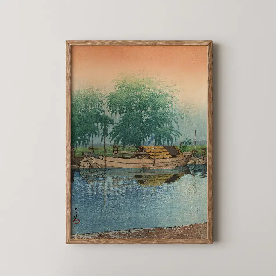 Framed painting of a serene riverside scene featuring traditional boats, greenery, and a gradient sky transitioning from orange to blue.