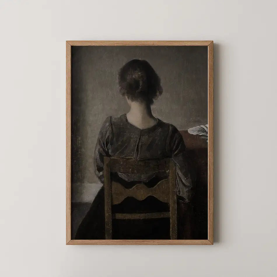 Framed painting of a woman sitting with her back to the viewer, depicting a muted color palette and a sense of solitude.