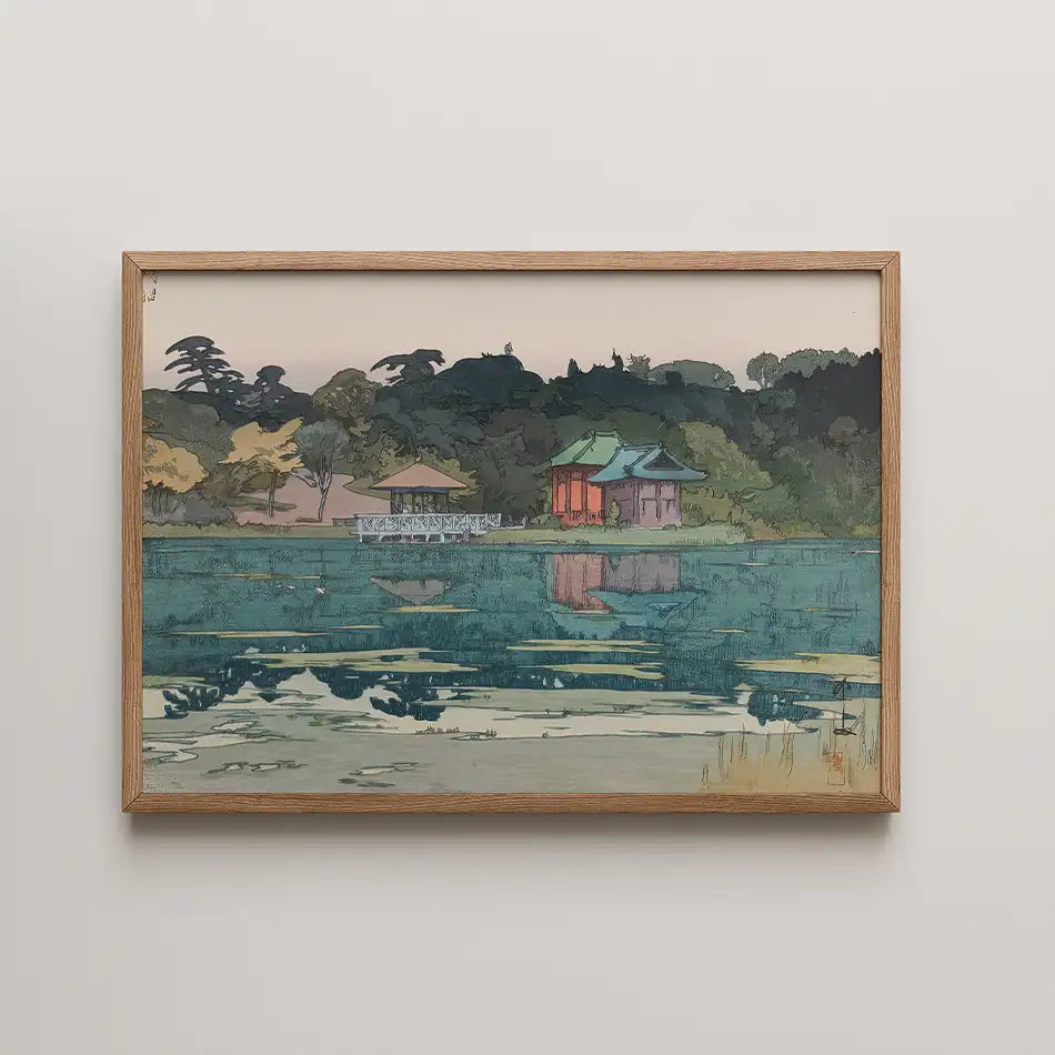 Framed painting of a serene lakeside scene featuring a traditional building, a gazebo, and lush greenery reflected in the water.