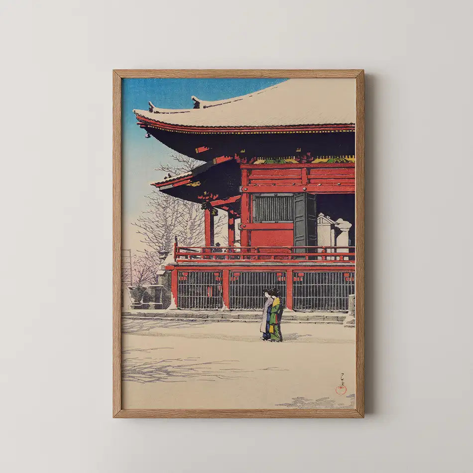 Framed painting of a traditional Japanese building with two figures in front, set against a blue sky.