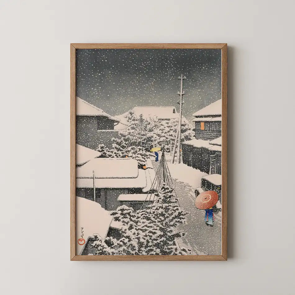 Framed painting depicting a snowy village scene with figures walking, traditional houses, and falling snowflakes.