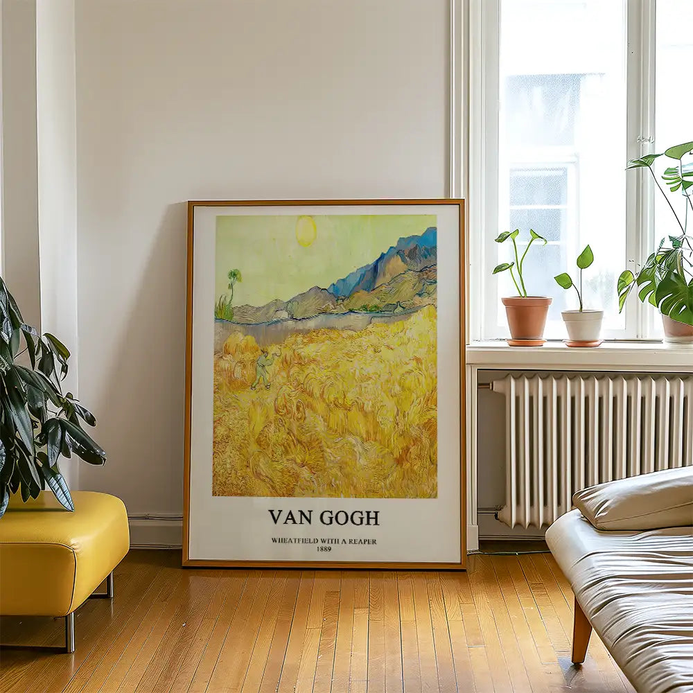 Framed painting titled "Wheatfield with a Reaper" by Van Gogh, displayed in a bright room with plants and modern furniture.