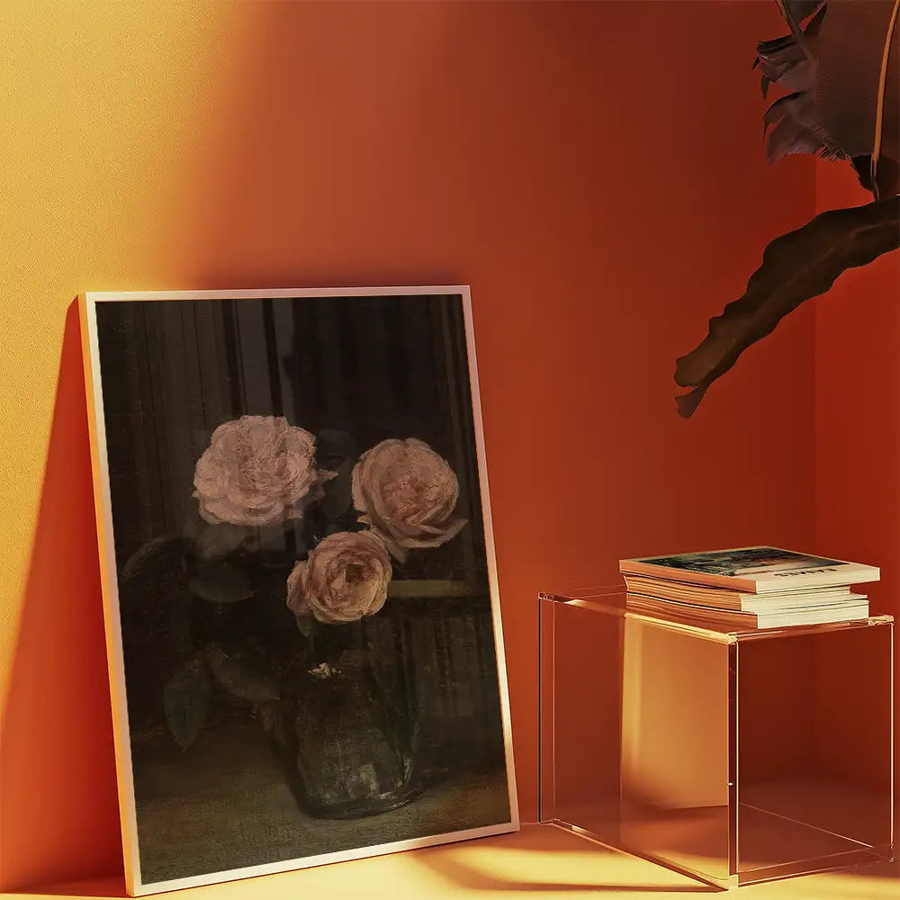 Framed painting of three roses in a vase, displayed on an orange wall next to a transparent side table with stacked books.