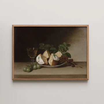 Still life painting featuring a plate of cheese, grapes, and a glass of drink, framed in natural wood.
