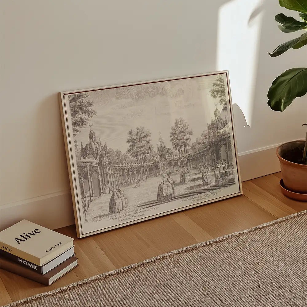 Framed vintage-style painting of a garden scene with figures, leaning against a wall in a minimalistic room setting with books and a plant.
