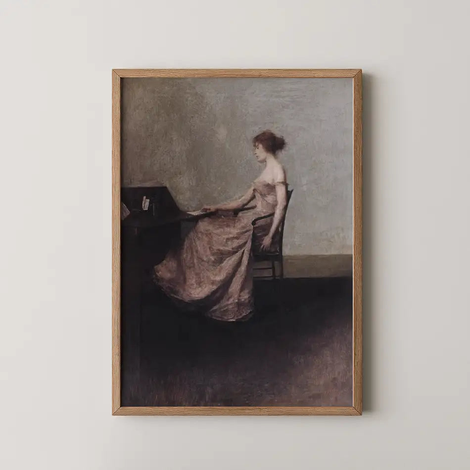 Painting of a seated woman in a pink dress, positioned at a desk with a muted background, framed in a wooden frame.