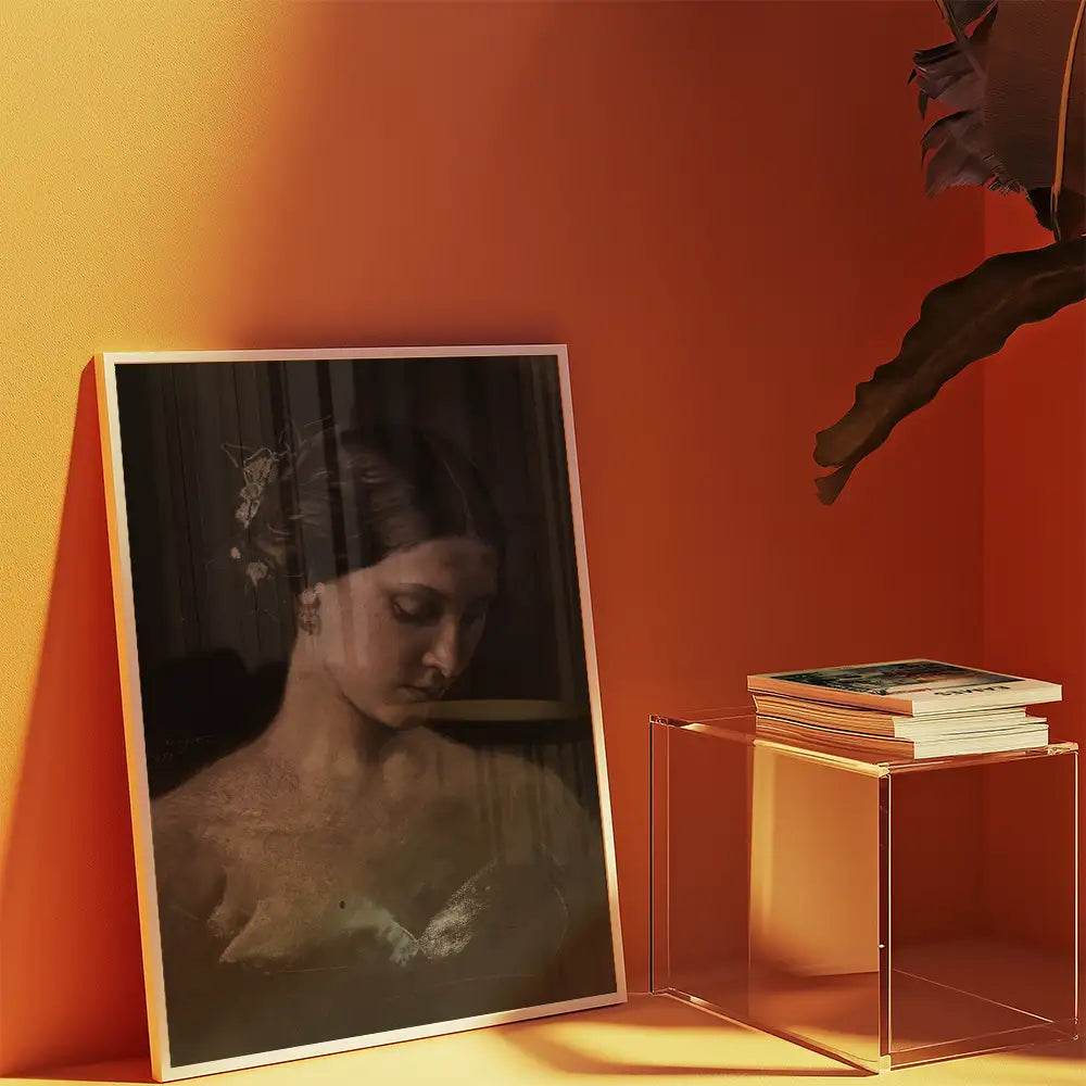 Framed painting of a woman with a serene expression, displayed against an orange wall, alongside stacked books and a clear acrylic table.