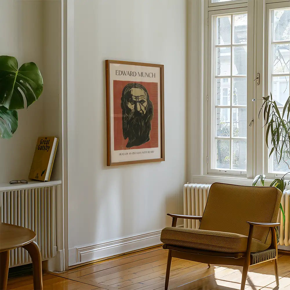 Framed poster of Edward Munch's artwork titled "Head of an Old Man" displayed on a wall in a modern living room with a chair and plant.