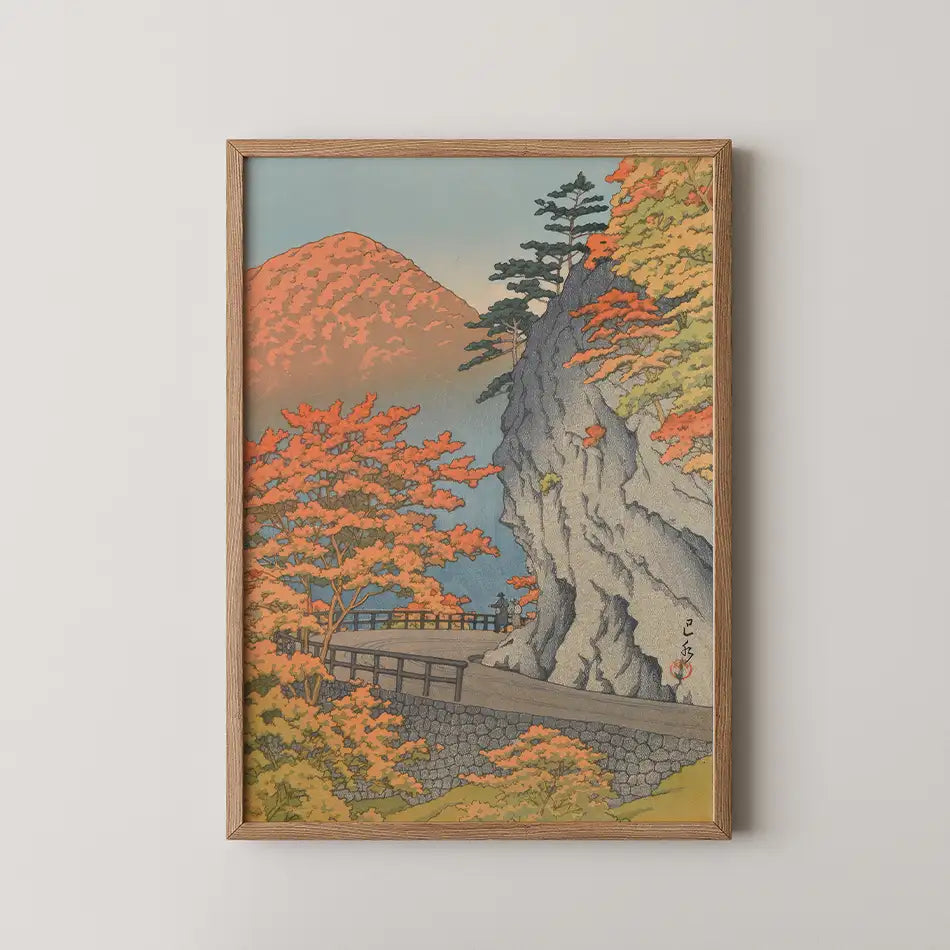 Framed painting of a scenic autumn landscape featuring vibrant orange trees, a rocky cliff, and a winding path along a waterway.