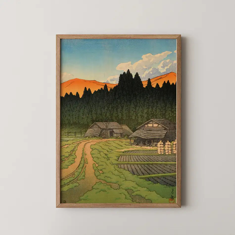Framed painting of a tranquil rural landscape featuring houses, a winding path, and a backdrop of mountains and trees under a colorful sky.