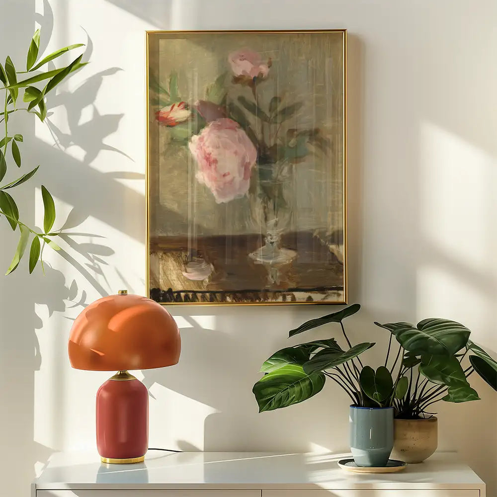 A soft, impressionistic painting of pink peonies in a glass vase, framed in gold, displayed on a wall beside a retro-style lamp and houseplants.