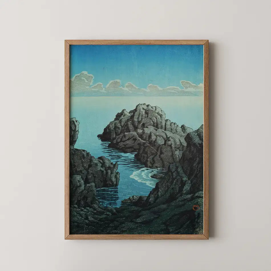Framed painting of a rocky coastline with calm waters and a blue sky, featuring clouds in the distance.