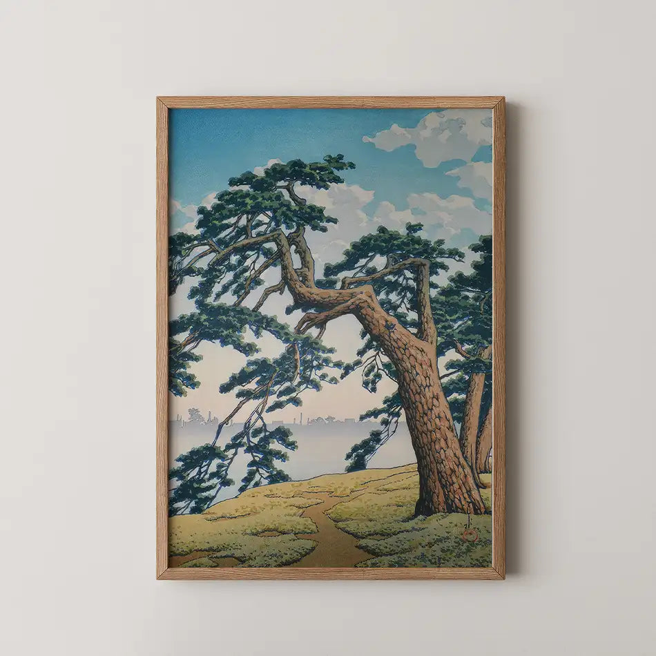 Framed painting of a landscape featuring trees and a winding path leading towards a body of water under a blue sky with clouds.