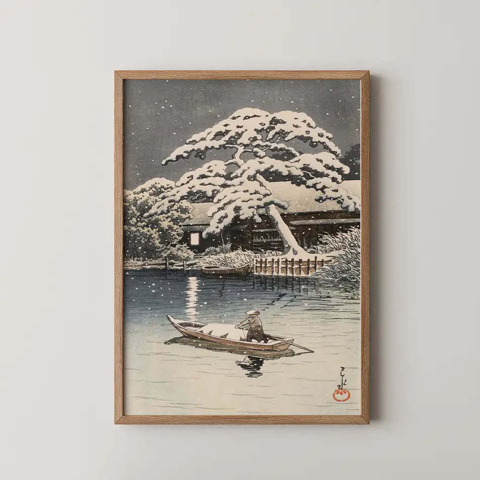 Framed painting of a snow-covered landscape featuring a lone figure in a boat on a calm river, surrounded by trees and a cottage in the background.