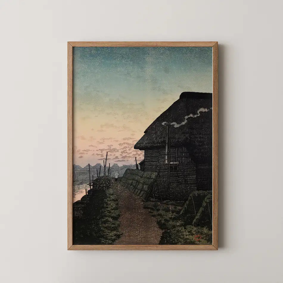 Framed painting of a rustic house at twilight with a path leading to the water, featuring soft pastel skies and smoke rising from the chimney.